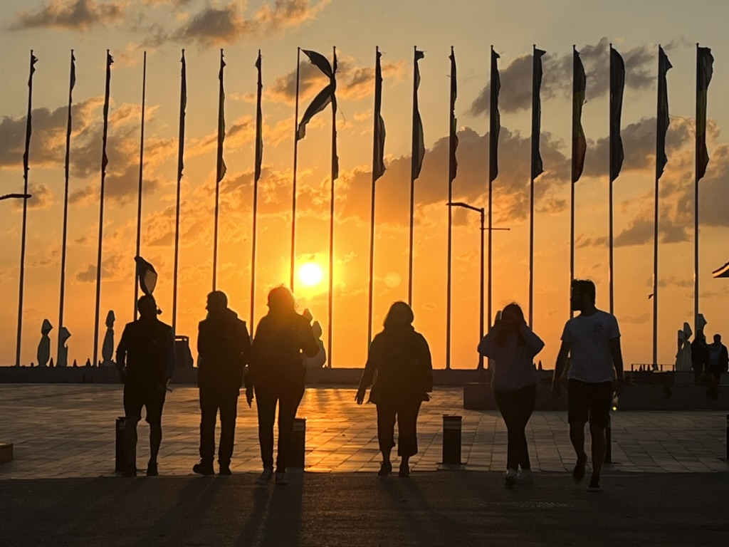 People walking among flags at sunset
